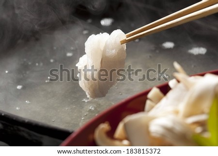 A piece of food being held with chopsticks.