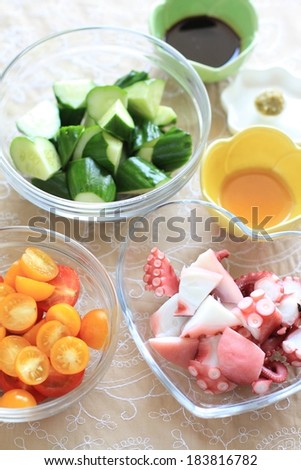 Chopped cucumbers surrounded with small bowls of other ingredients.