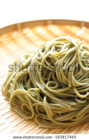 A pile of green noodles on a woven plate.