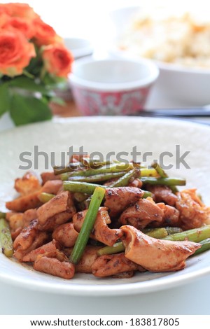 A plate of meat and vegetables with flowers and a cup in the background.