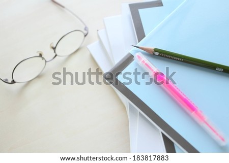 Glasses beside several file folders with writing utensils on top.