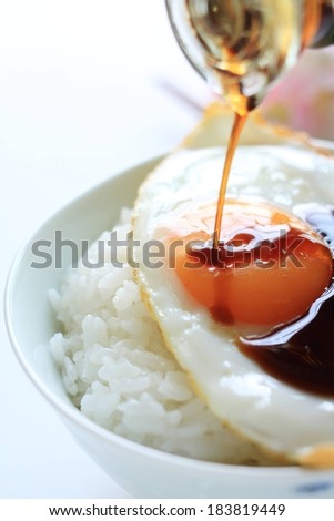 A bed of white rice with a sunny side up egg and au jus being drizzled.