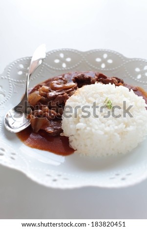 A rice and meat dish in a sauce on a patterned plate.