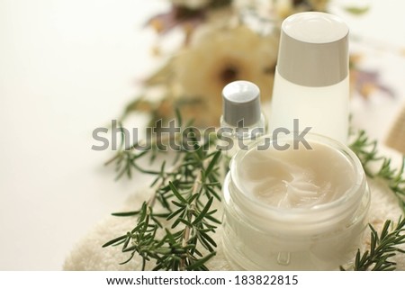 Assorted creams and skincare products surrounded by a herb.