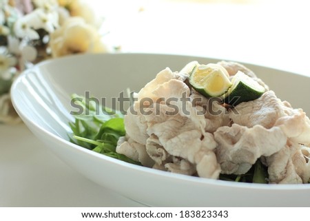 A dish of meat and leafy greens topped with lime.