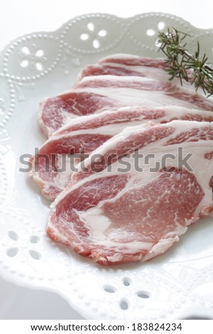 Cuts of meat on a decorative white plate topped by a sprig.