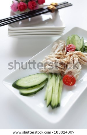 A rectangular dish filled with food with dishes and chopsticks above.