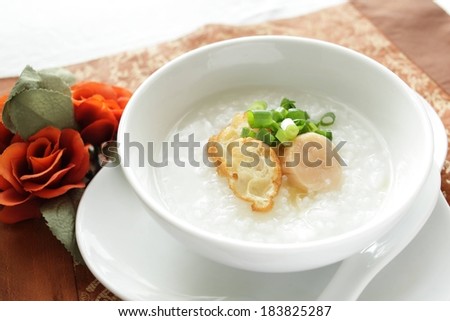 A white bowl filled with food placed on a white plate.