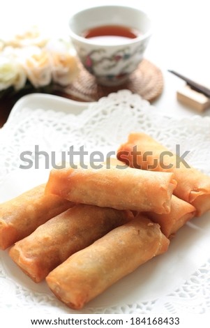 A stack of egg rolls on a plate with lace.