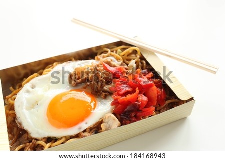 A cardboard box filled with fried egg and noodles.