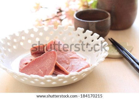 Slices of meat in a decorative bowl, with a pair of chop sticks.
