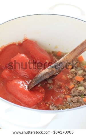 Mixing fresh roma tomatoes with seasoned ground meat.