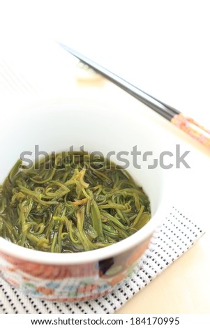 A bowl of green noodles sitting on a cloth.