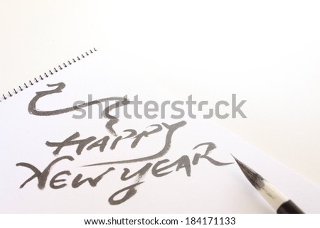 A piece of paper that reads \'Happy New Year\' in black paint.
