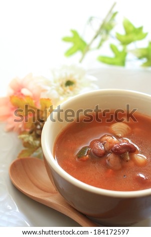 A small bowl of chili on a dish with a spoon.