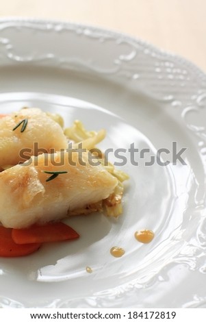 A white dish is full of food and sits on a table.