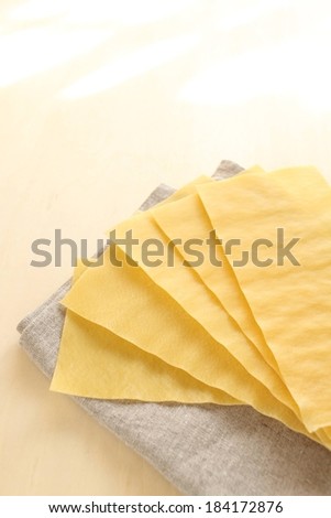 Five layered sheets of lasagne pasta fanned out on a folded cloth.