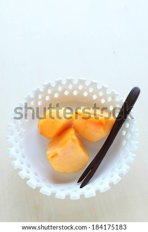 A small white bowl holding three pieces of food with a fork.