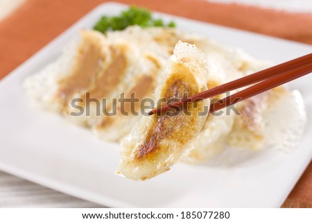 Fried Chinese dumplings being picked up with chop sticks.