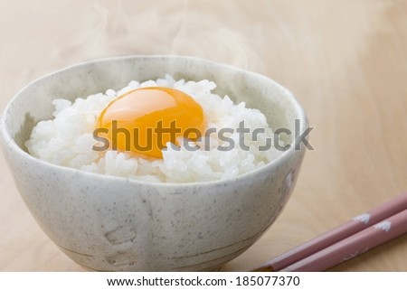 A steaming hot bowl of rice with an egg yolk.