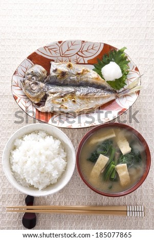 A decorative plate with a fish and garnish and side dishes.