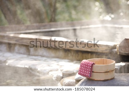 A wooden bowl with a folded towel, and a steaming hot spring.