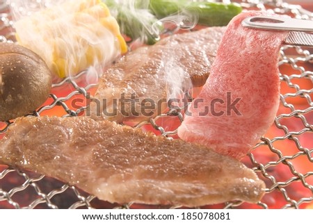 Several slices of meat and veggies grilling on a grill.