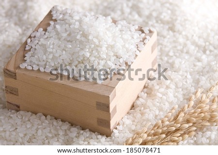 A brown box overflowing with white rice and completely surrounded by it.