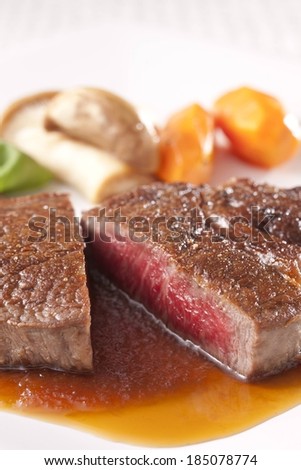 A medium rare steak and side dishes with juices.