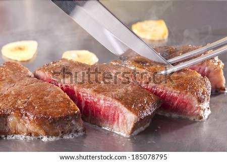 A piece of meat is being cut into small pieces.