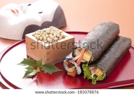 Food wraps and a box of nuts or seeds set on a red plate alongside a mask.