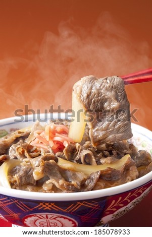 Steaming hot Asian meal of mixed vegetables and meat being eaten with chop sticks.