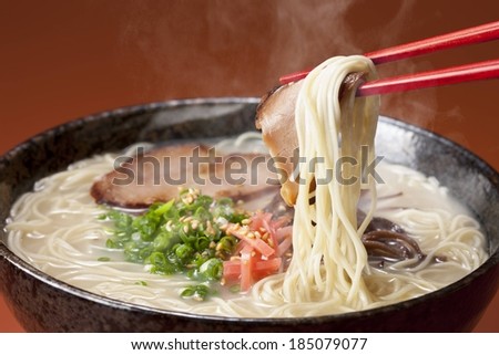 A ceramic bowl filled with a steaming dish of noodles, meat, and vegetables.