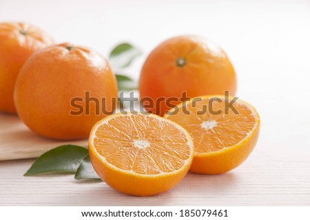 An orange cut in half and three whole oranges.