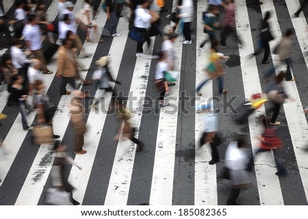 A city cross walk is littered with pedestrians.