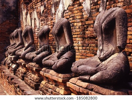 A row of stone headless statues on bricks.