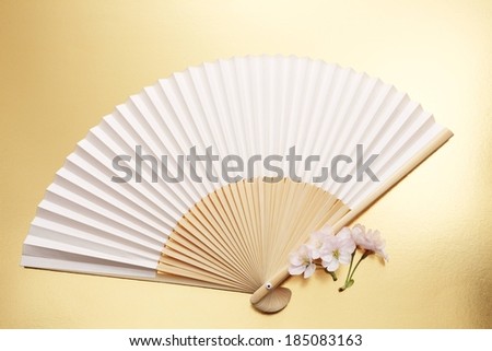 A Chinese fan with three flowers beside it.