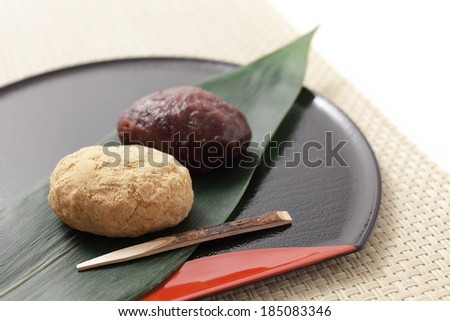Food items and a wooden skewer resting on a large leaf.