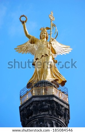 A golden statue of an angel with wings atop the Victory Column, Berlin.