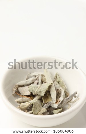 A white bowl with some dry herb leaves in it.