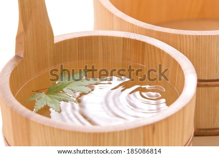 A wooden bucket full of water and two leaves.