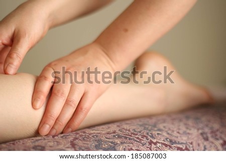 Two hands rubbing the back of a person\'s calves.
