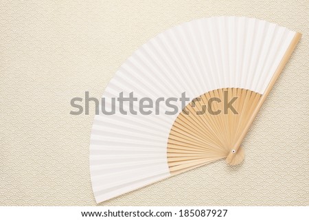 A white fan spread out on a beige cloth.