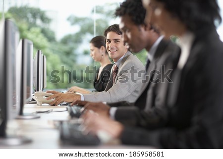 Office workers using computers, man reaching for telephone