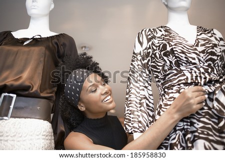 Young woman adjusting dress on mannequin