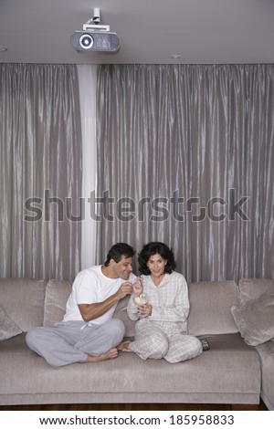 Mid adult couple eating ice cream and watching TV