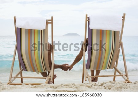 Couple on lounge chairs, holding hands (rear view), St. John, US Virgin Islands, USA