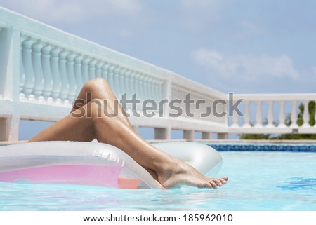 Woman lying on pool raft (focus on legs)