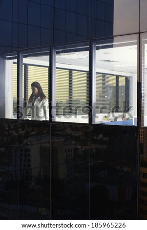 Businesswoman looking through office window (exterior view)