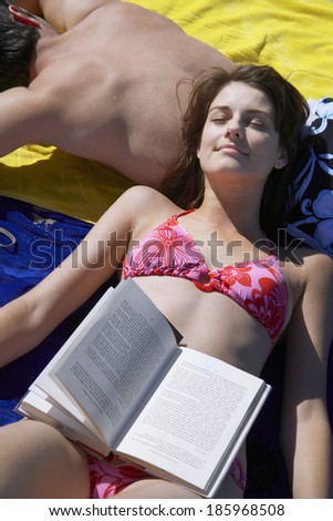 Young woman sunbathing and resting head on boyfriend\'s back (high angle view)